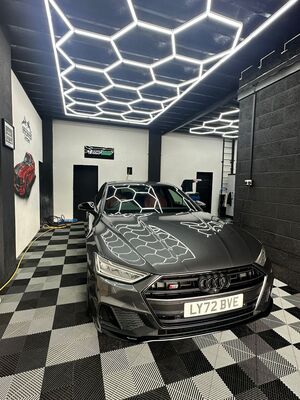 Dark grey Audi sedan front view showing paint reflection after machine polishing