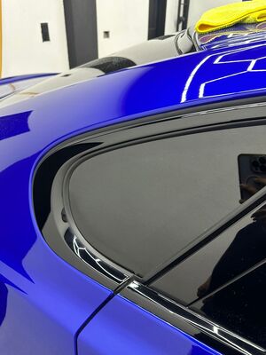 High-gloss blue paint reflection on the rear quarter of a Jaguar XE