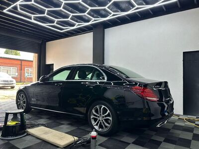 Mirror-like reflection on the black paintwork of a detailed Mercedes-Benz sedan