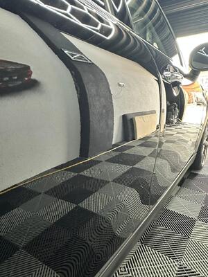 Flawless mirror-like paint reflection on the side panel of a black Mini Cooper after car detailing