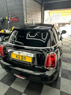 Polished black paintwork and clean taillights on the rear of a Mini Cooper after paint correction