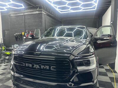 Front view of a massive black RAM pickup truck detailed under studio lights in Liverpool