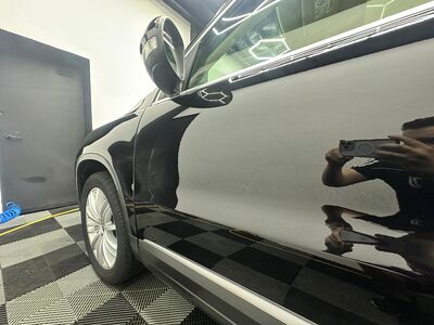 Mirror-like reflection on the black side panels of a Volvo XC90 SUV